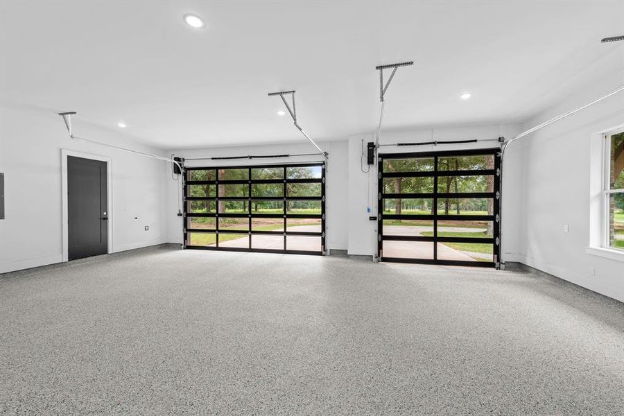 3 full car glass door garage space with epoxy flooring, exterior door to backyard and storage closet.