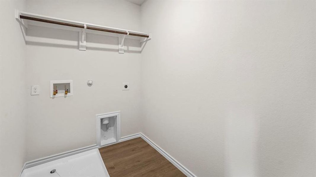 Laundry room with light-colored walls, wood-look flooring, and a clothes hanging rod with shelving