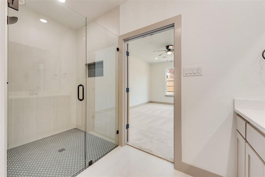 Bathroom featuring walk in shower, ceiling fan, and vanity