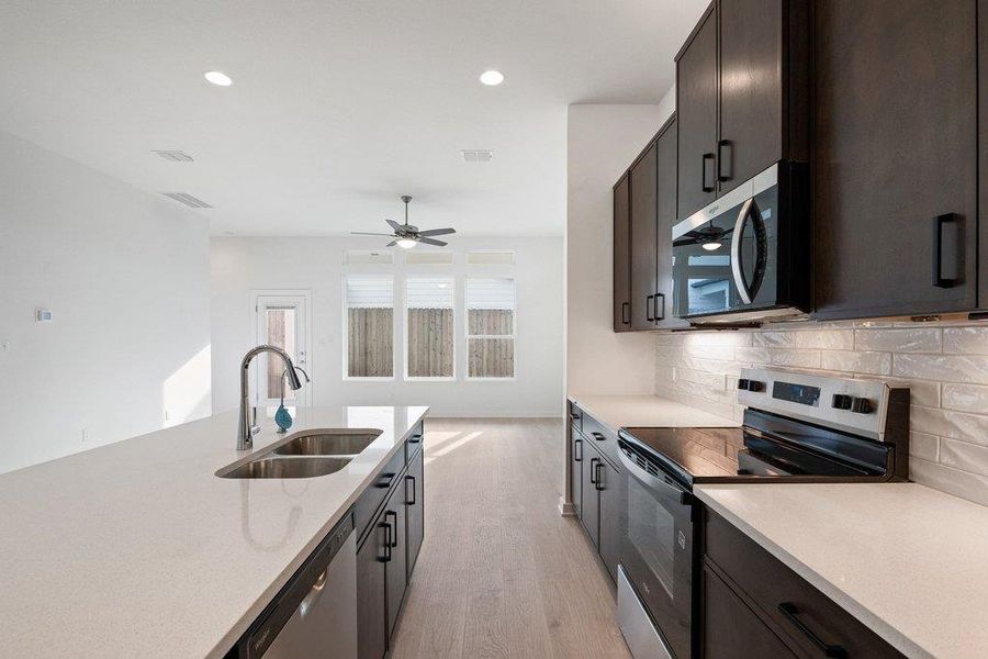 Kitchen featuring stainless steel appliances, light wood-type flooring, light stone counters, recessed lighting, and decorative backsplash