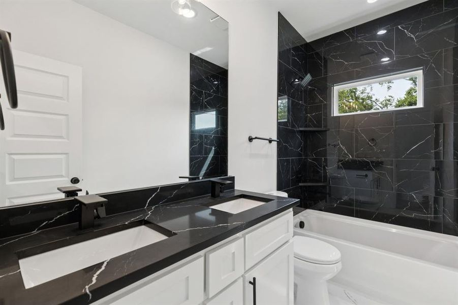 Full bath featuring double vanity and a combined bath / shower with marble appearance