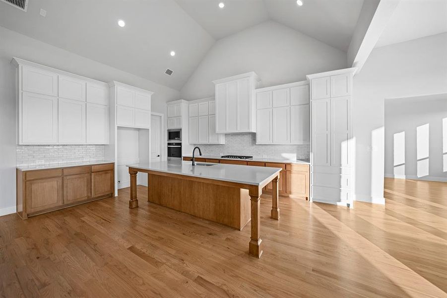 Kitchen with a kitchen breakfast bar, high vaulted ceiling, white cabinets, decorative backsplash, and recessed lighting Kitchen with a kitchen breakfast bar, high vaulted ceiling, white cabinets, decorative backsplash, and recessed lighting