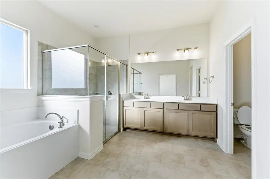 Bathroom featuring a garden tub, double vanity, and a shower stall