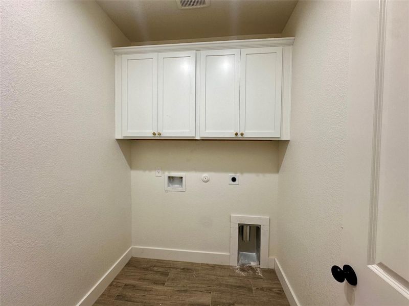 Clothes washing area featuring electric dryer hookup, cabinet space, washer hookup, dark wood finished floors, and hookup for a gas dryer Clothes washing area featuring electric dryer hookup, cabinet space, washer hookup, dark wood finished floors, and hookup for a gas dryer