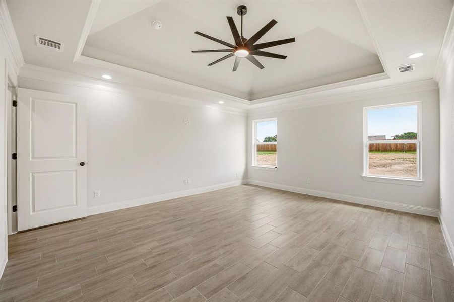 Spare room with ceiling fan, wood finish floors, ornamental molding, recessed lighting, and a raised ceiling