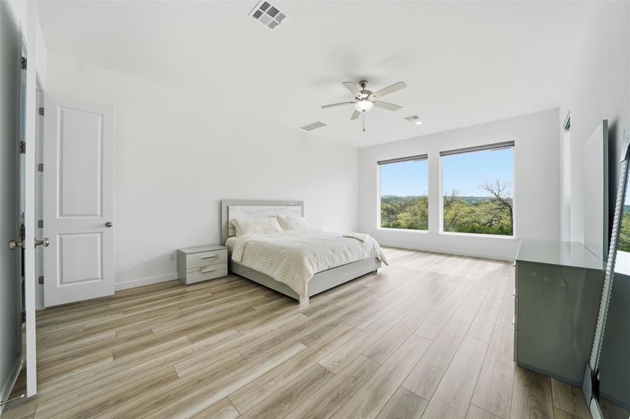 Bright room featuring light-toned flooring, white walls, and large windows offering a lush green view