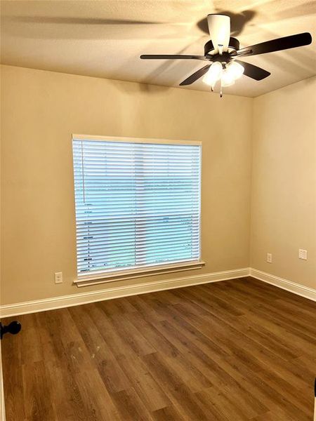 Empty room with a ceiling fan, dark wood finished floors, and baseboards Empty room with a ceiling fan, dark wood finished floors, and baseboards