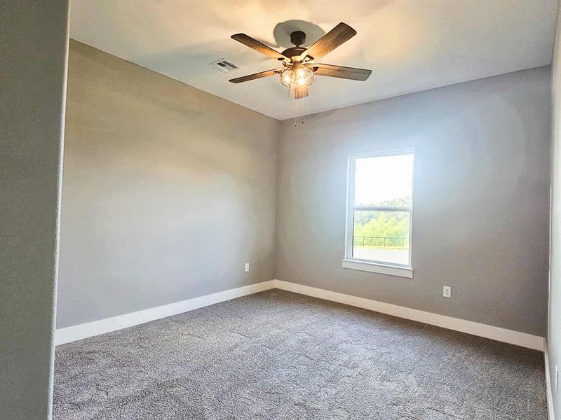 Third bedroom w/ ceiling fan, carpet, and large closet w/ storage shelves.