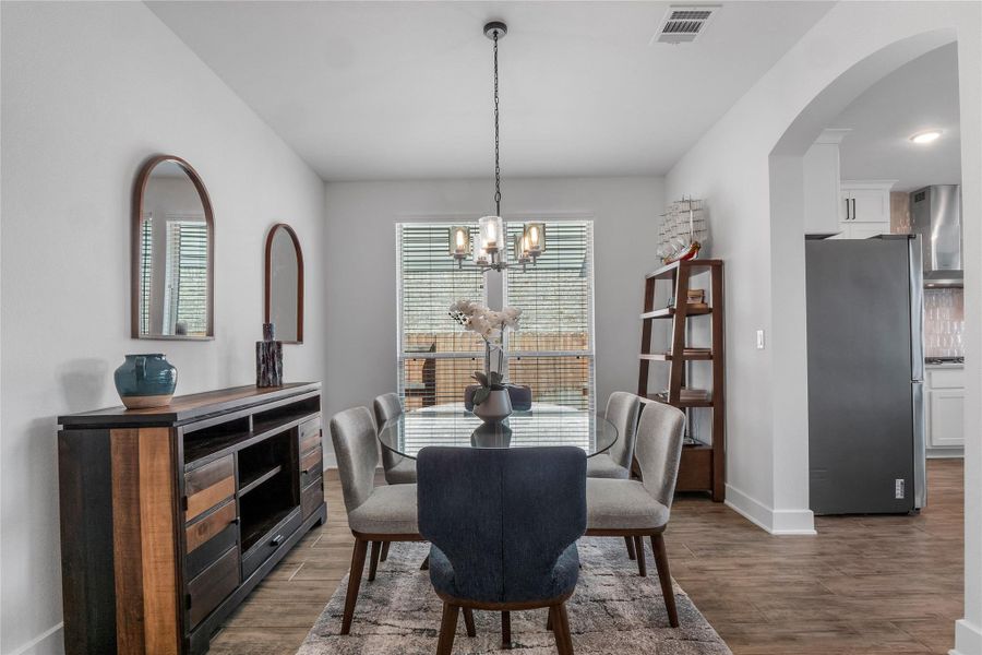 Dining space with arched walkways, a chandelier, and dark wood finished floors Dining space with arched walkways, a chandelier, and dark wood finished floors