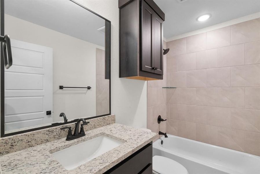 Full bathroom with vanity, tiled shower / bath combo, and toilet Full bathroom with vanity, tiled shower / bath combo, and toilet