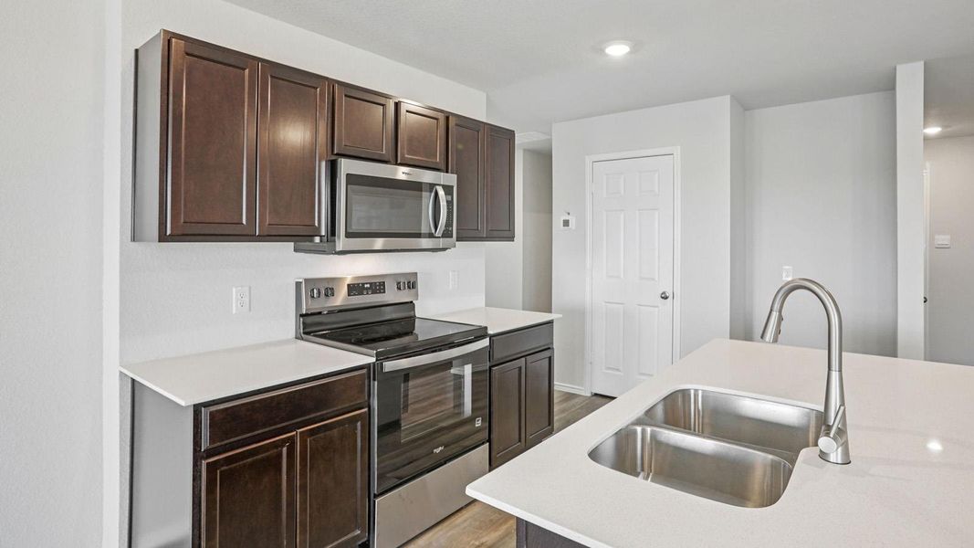 A contemporary kitchen showcasing dark cabinetry, white countertops, and sleek stainless steel appliances. A contemporary kitchen showcasing dark cabinetry, white countertops, and sleek stainless steel appliances.