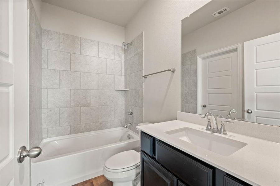 Primary Bath with tiled shower, Quartz countertops, Walk-in Closet (door shown in Mirror)