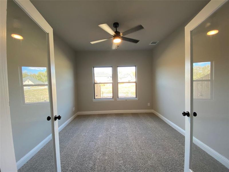 Bright study with modern glass double doors and a ceiling fan