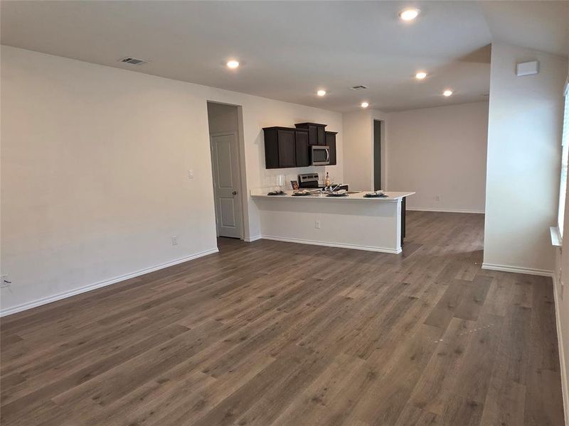 Kitchen featuring a peninsula, dark cabinetry, dark wood-type flooring, appliances with stainless steel finishes, and recessed lighting Kitchen featuring a peninsula, dark cabinetry, dark wood-type flooring, appliances with stainless steel finishes, and recessed lighting