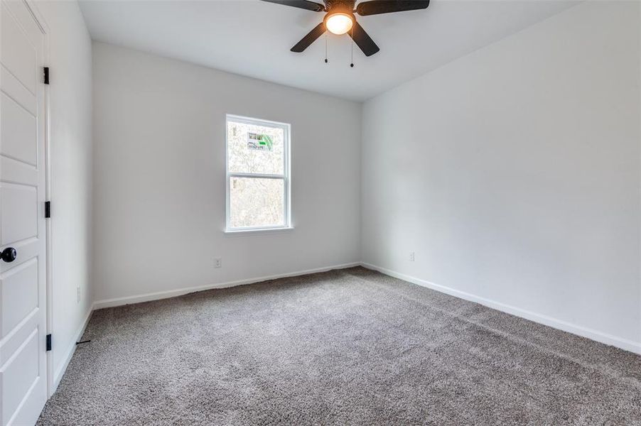 Carpeted empty room featuring ceiling fan