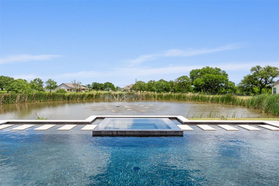 Dock area with a water view, a patio area, a pool with connected hot tub, and view of wooded area