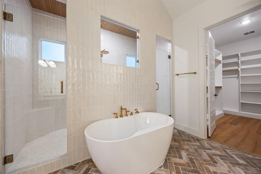 Bathroom featuring a stall shower, a spacious closet, and a freestanding bath
