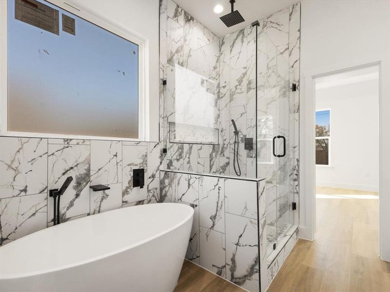 Bathroom with a freestanding tub, a marble finish shower, and wood finished floors