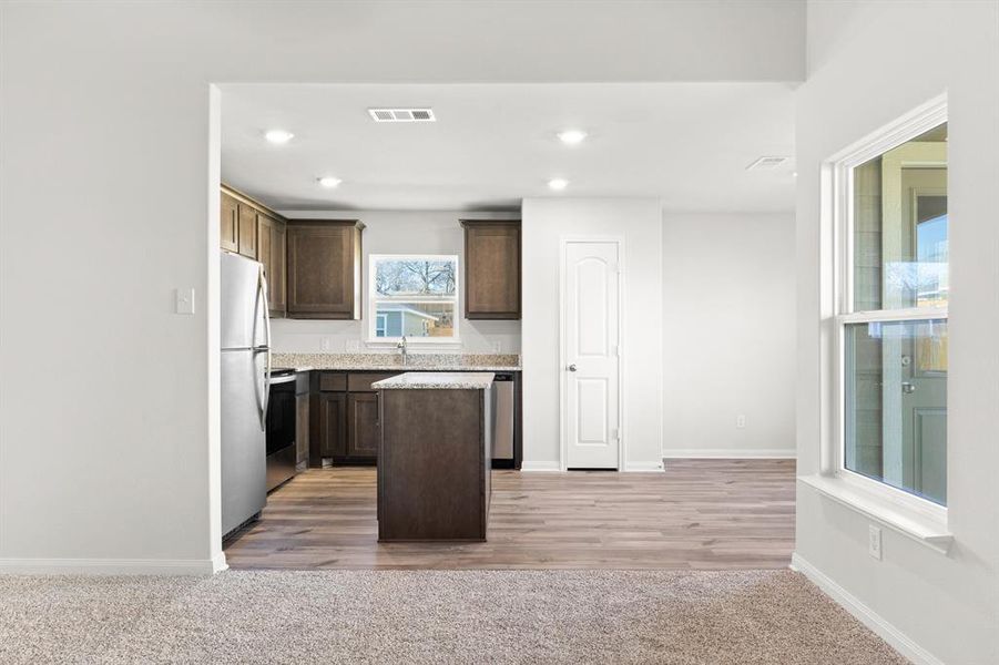 Kitchen featuring dark brown cabinetry, stainless steel appliances, light hardwood / wood-style flooring, and a kitchen island