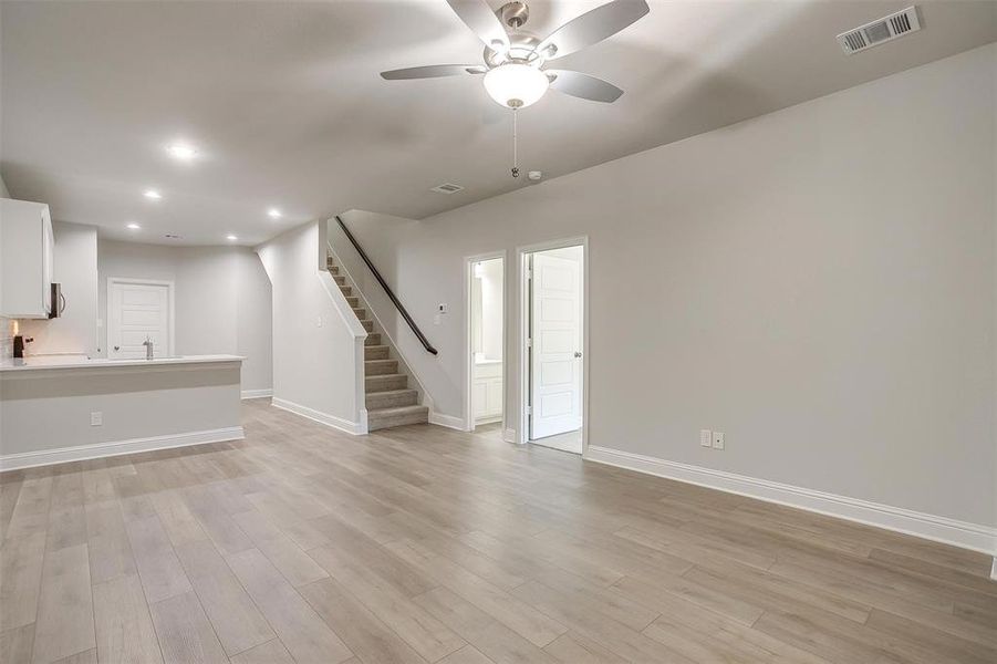 Unfurnished living room featuring a ceiling fan, stairway, light wood-style flooring, and recessed lighting Unfurnished living room featuring a ceiling fan, stairway, light wood-style flooring, and recessed lighting