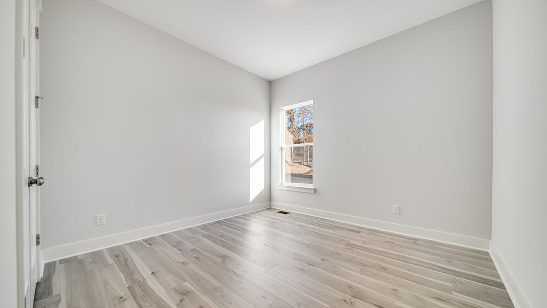 Secondary bedroom with hard-surface flooring and large window