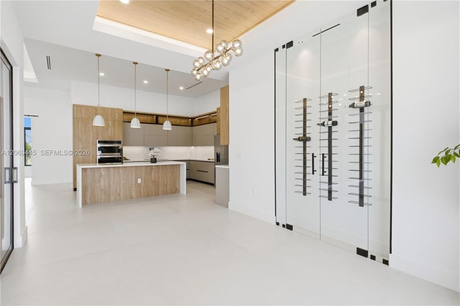 Elegant dining area features a wood-accent tray ceiling, designer chandelier and striking glass-enclosed wine display. Elegant dining area features a wood-accent tray ceiling, designer chandelier and striking glass-enclosed wine display.
