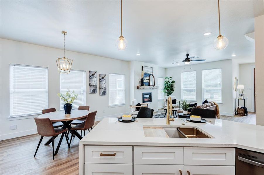 Kitchen featuring sink, dishwasher, light wood-type flooring, and pendant lighting