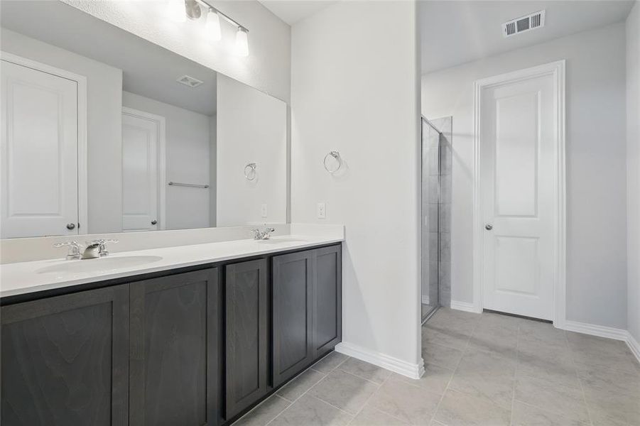 Full bath with double vanity, a shower stall, and tile patterned flooring Full bath with double vanity, a shower stall, and tile patterned flooring