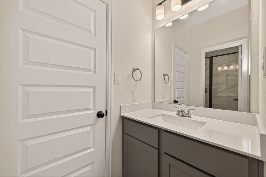 This bathroom features a sleek vanity with a modern sink and faucet, large mirror, and stylish lighting. The neutral color palette and clean lines provide a contemporary feel.