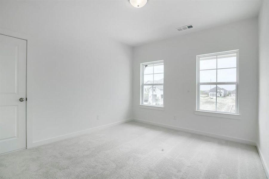 Bright interior room featuring light-colored carpeting, white painted walls, and two large windows with white trim