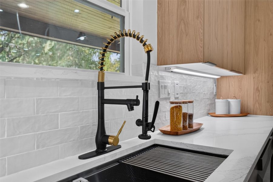 Sleek kitchen with a modern black and gold faucet, white marble countertops, and elegant wood cabinetry, offering a stylish and functional space.