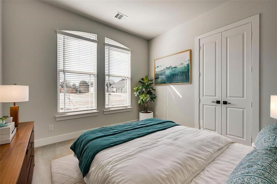 Bedroom featuring visible vents, baseboards, a closet, and light carpet