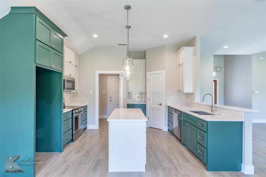 Kitchen featuring a center island, appliances with stainless steel finishes, decorative backsplash, a peninsula, and recessed lighting