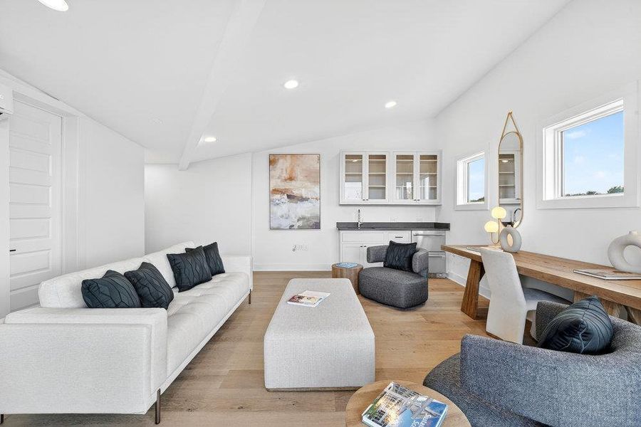 Living area with light wood-type flooring, vaulted ceiling, and recessed lighting