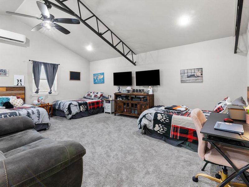 Carpeted bedroom featuring high vaulted ceiling, a ceiling fan, and a wall mounted AC