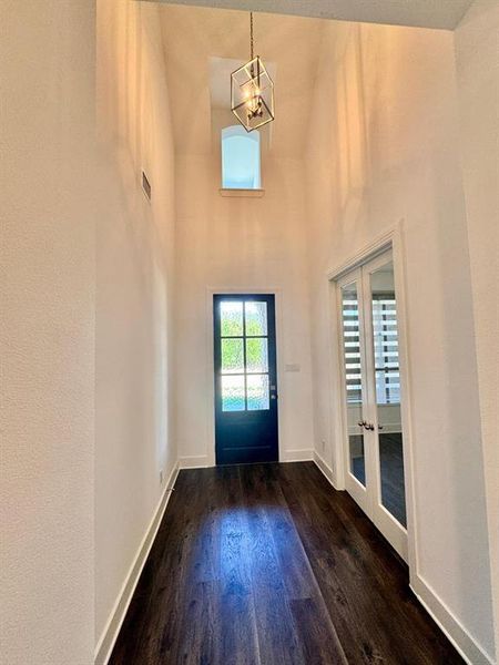 Entrance foyer with dark wood-type flooring, high vaulted ceiling, and a chandelier