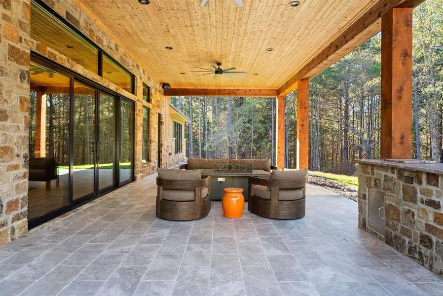 View of patio featuring an outdoor hangout area, a ceiling fan, and view of wooded area