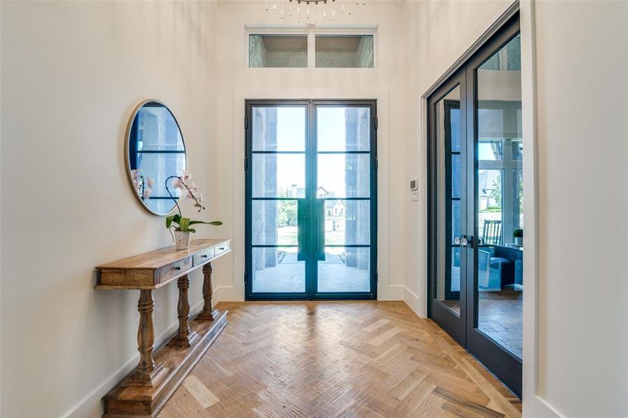 Foyer entrance with light parquet flooring and french doors