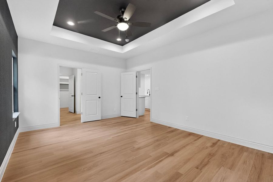 Spacious room featuring wood-finish flooring, a tray ceiling with a dark accent, and recessed lighting Spacious room featuring wood-finish flooring, a tray ceiling with a dark accent, and recessed lighting