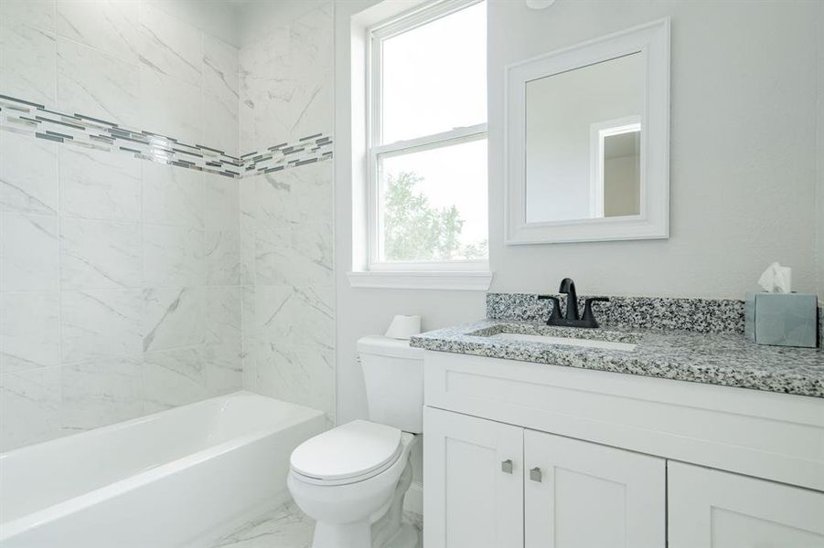 Full bathroom with vanity, tiled shower / bath, and toilet