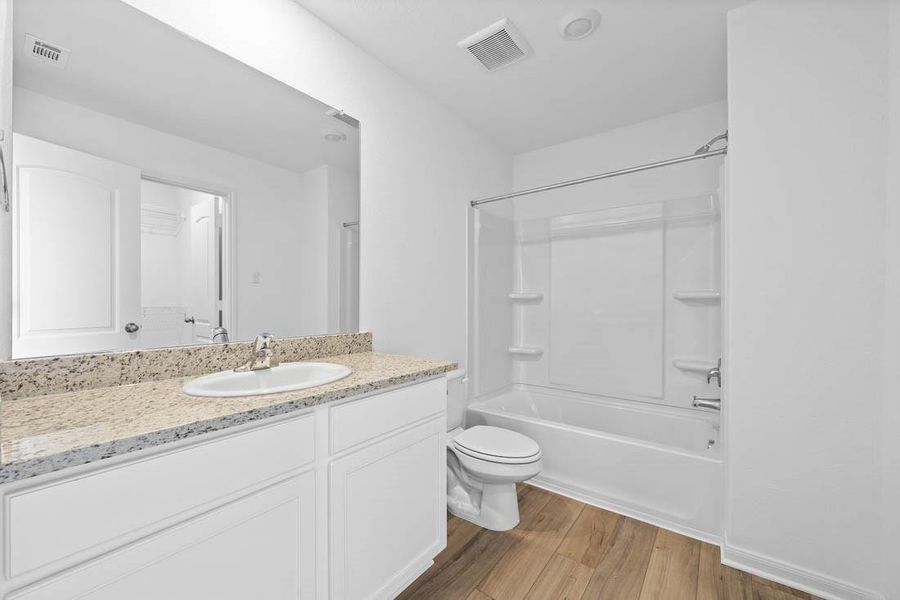 Full bathroom off guest room includes granite counters, designer white cabinetry and luxury vinyl plank flooring.