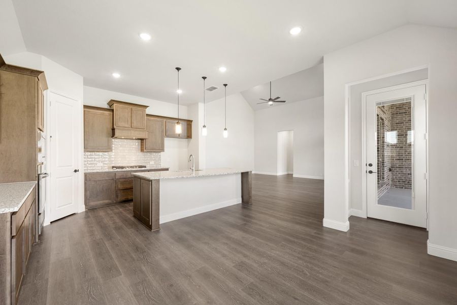Open kitchen with wood cabinets, center island, pendant lights, and dark hardwood floors opening to living area Open kitchen with wood cabinets, center island, pendant lights, and dark hardwood floors opening to living area