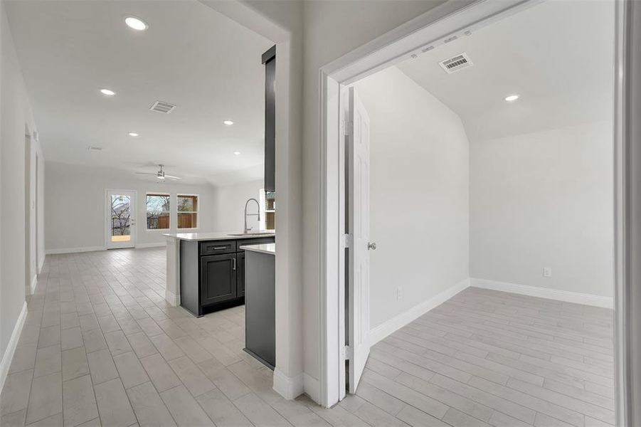 Hallway with light wood-style floors, visible vents, a sink, and recessed lighting Hallway with light wood-style floors, visible vents, a sink, and recessed lighting