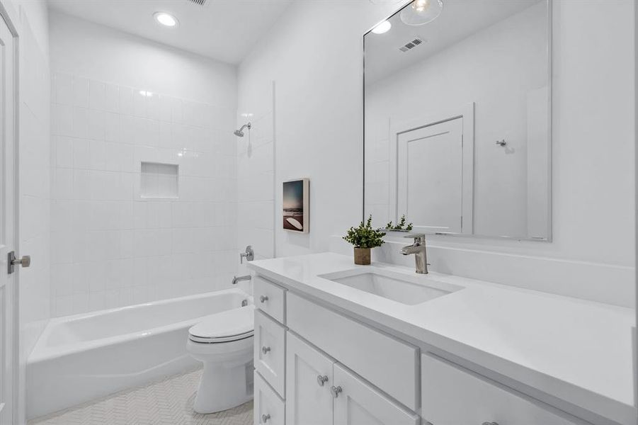 Full bathroom with tiled shower / bath combo, vanity, tile patterned floors, and toilet