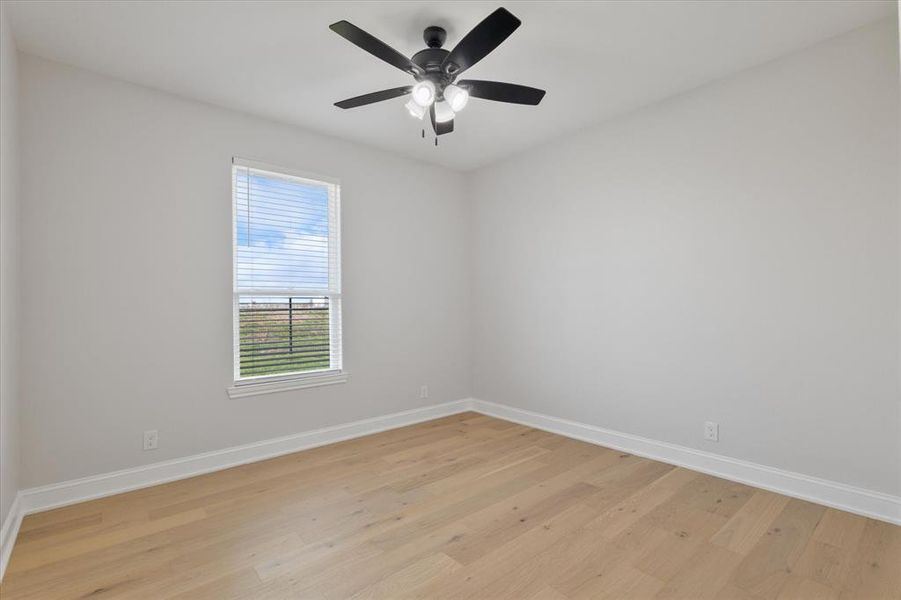 Unfurnished room with light wood-style floors, ceiling fan, and baseboards