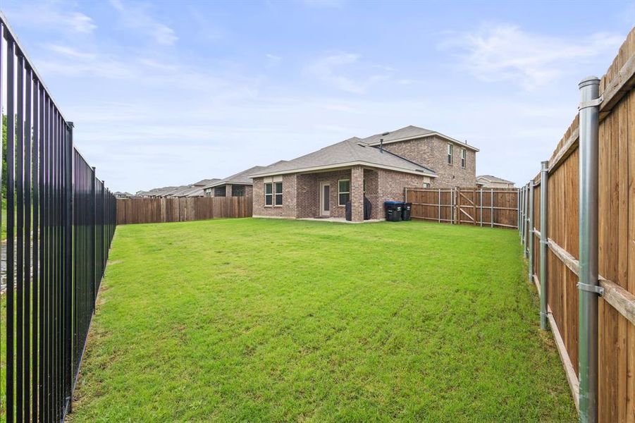 Expansive backyard featuring a well-maintained lawn and a combination of wood and metal fencing Expansive backyard featuring a well-maintained lawn and a combination of wood and metal fencing