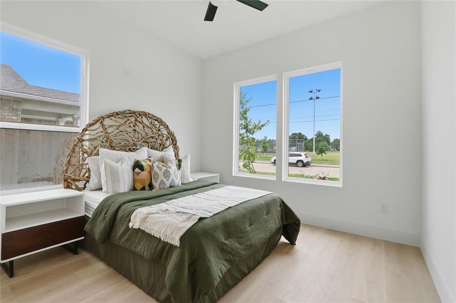 Bedroom featuring light wood-finish flooring, white walls, and a black ceiling fan Bedroom featuring light wood-finish flooring, white walls, and a black ceiling fan