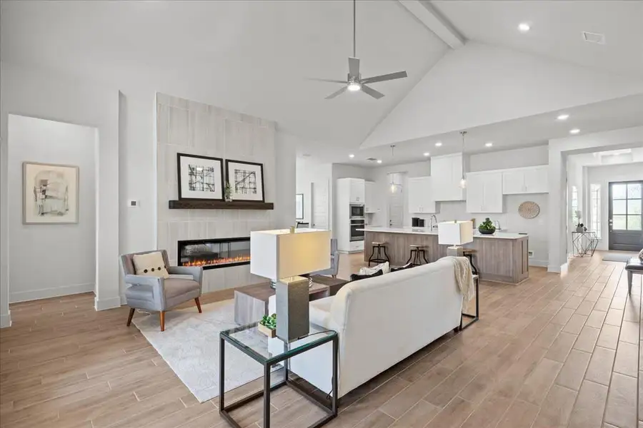 Living room featuring *PHOTO REPRESENTATIVE OF FLOORPLAN ONLY*ceiling, light wood-style flooring, high vaulted ceiling, ceiling fan, and a tile fireplace
