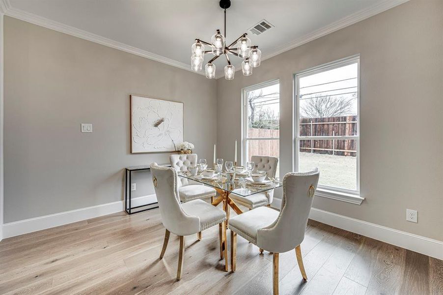 Dining room with a notable chandelier, ornamental molding, and light wood-type flooring