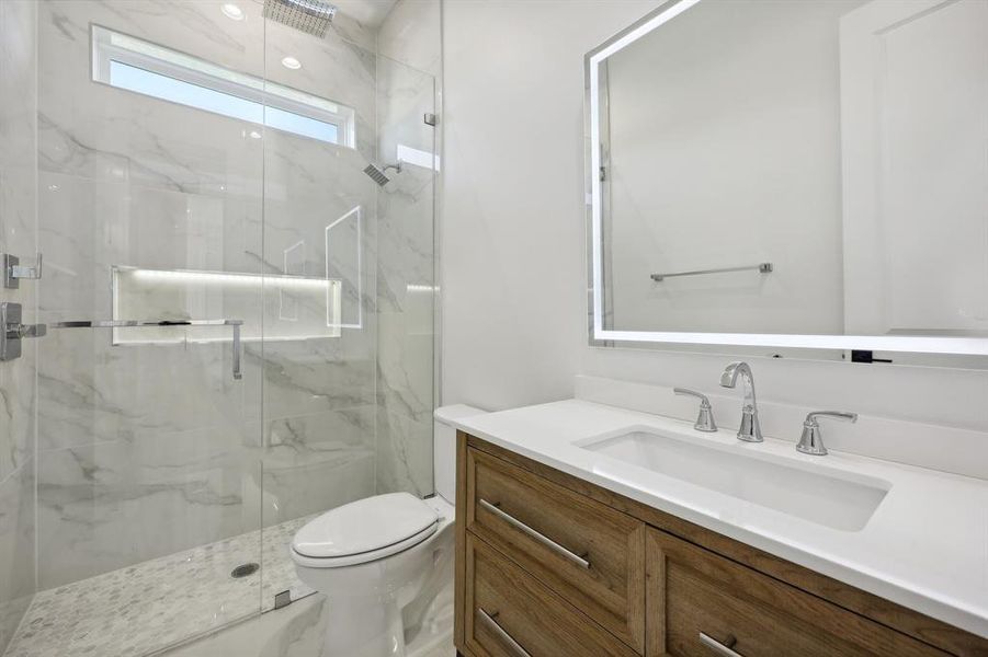 Bathroom featuring vanity, toilet, and an enclosed shower